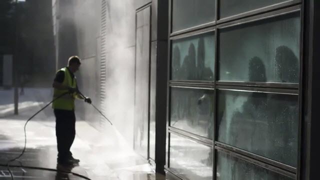 commercial pressure washing professional spraying the concrete outside of commercial property on Long Island